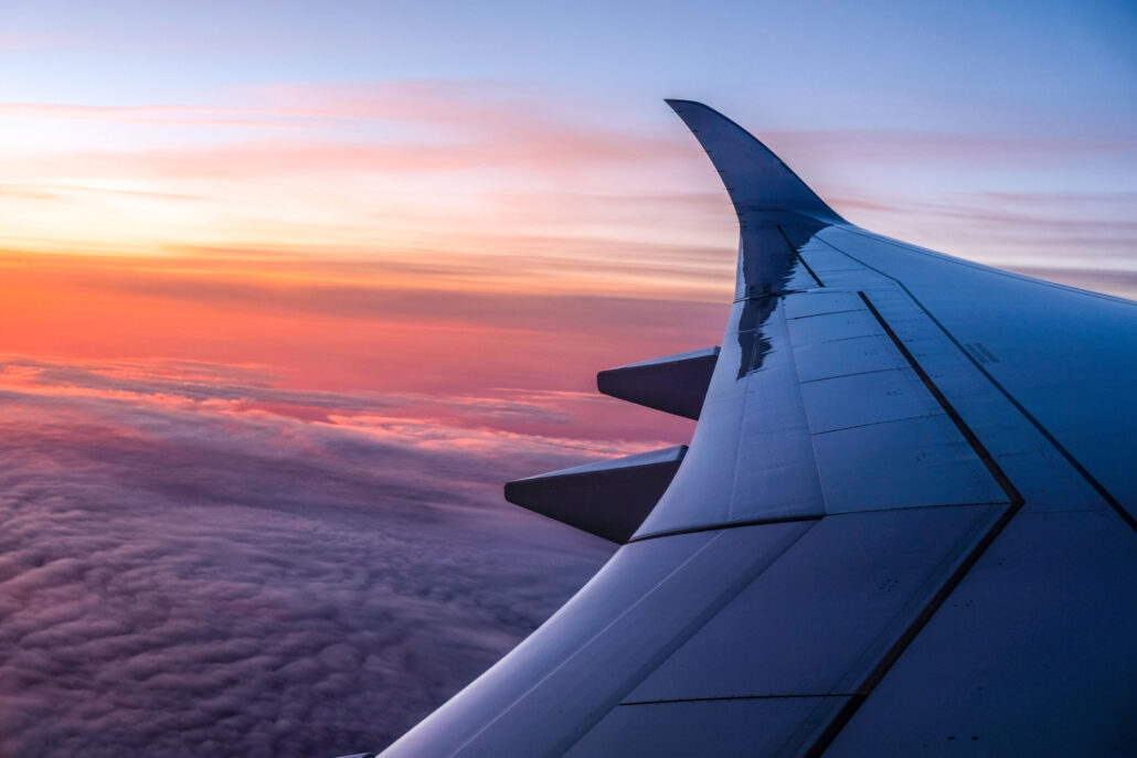 Airplane wing above the clouds at sunset